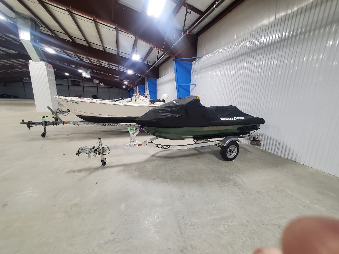 A boat and a personal watercraft on trailers in indoor storage