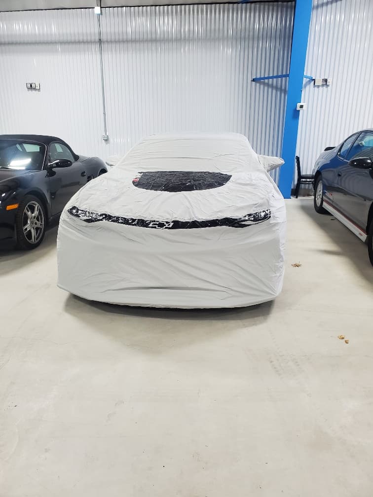 A car under a fitted cover in its bay