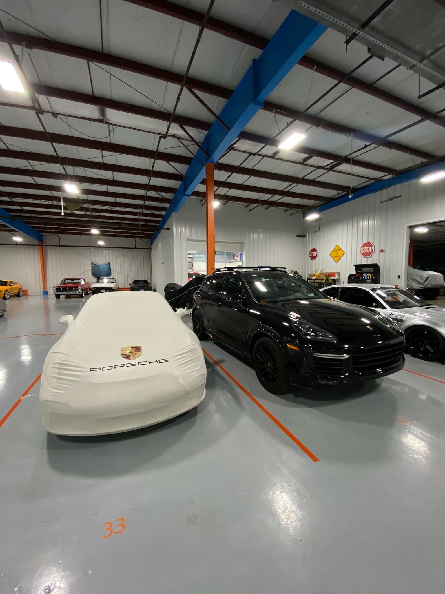 A row of covered Porsches inside the vehicle building